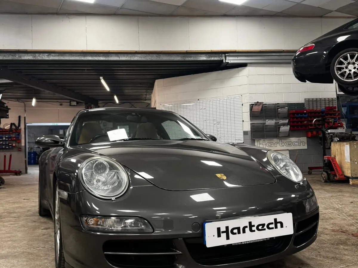A dark grey 997 Carrera in the workshop with a Hartech plate on the front.