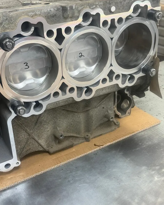 Crankcase half with three new liners, pistons numbered 2 and 3 visible in the bores.