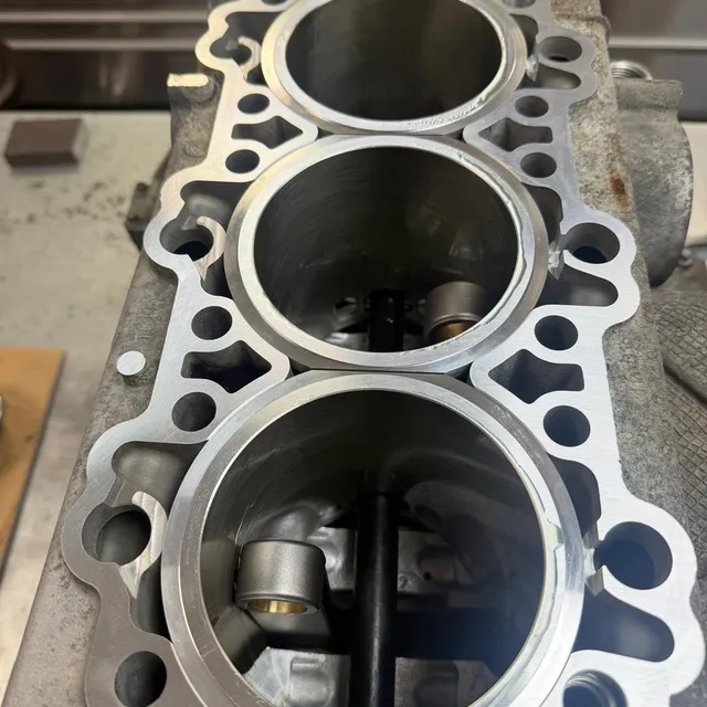 Looking straight down three cylinder bores in a crankcase half, with the crankshaft visible at the bottom.