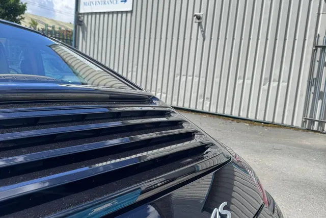 The rear of a black 997 Carrera 4S in the yard, with the Hartech sign and the entrance signs on the building behind.