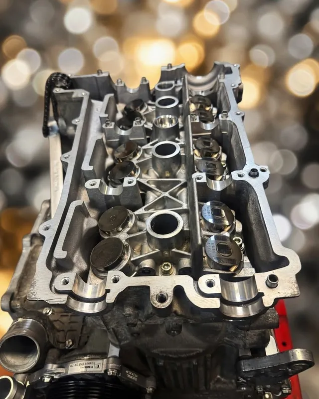 A cylinder head on the bench with the camshafts removed and the valve gear exposed.