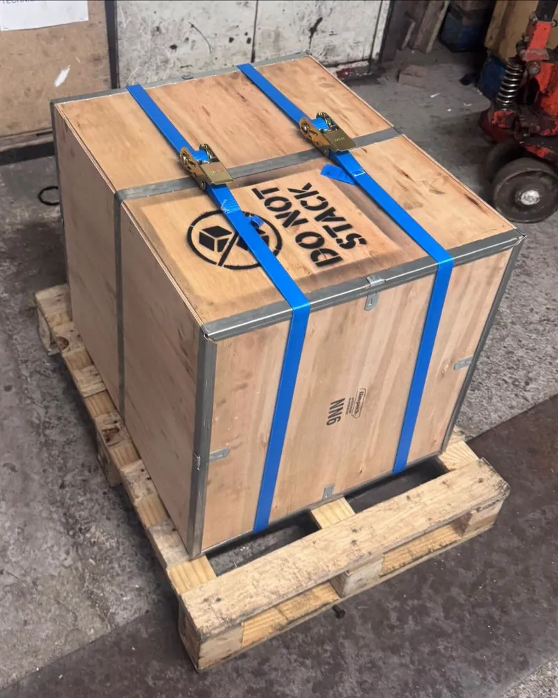 A wooden shipping crate strapped to a pallet in the workshop, stencilled Do Not Stack.