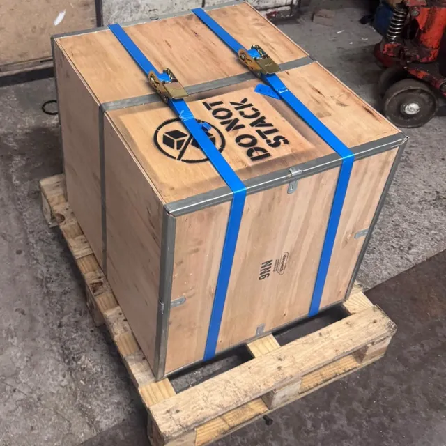 A wooden shipping crate strapped to a pallet in the workshop, stencilled Do Not Stack.