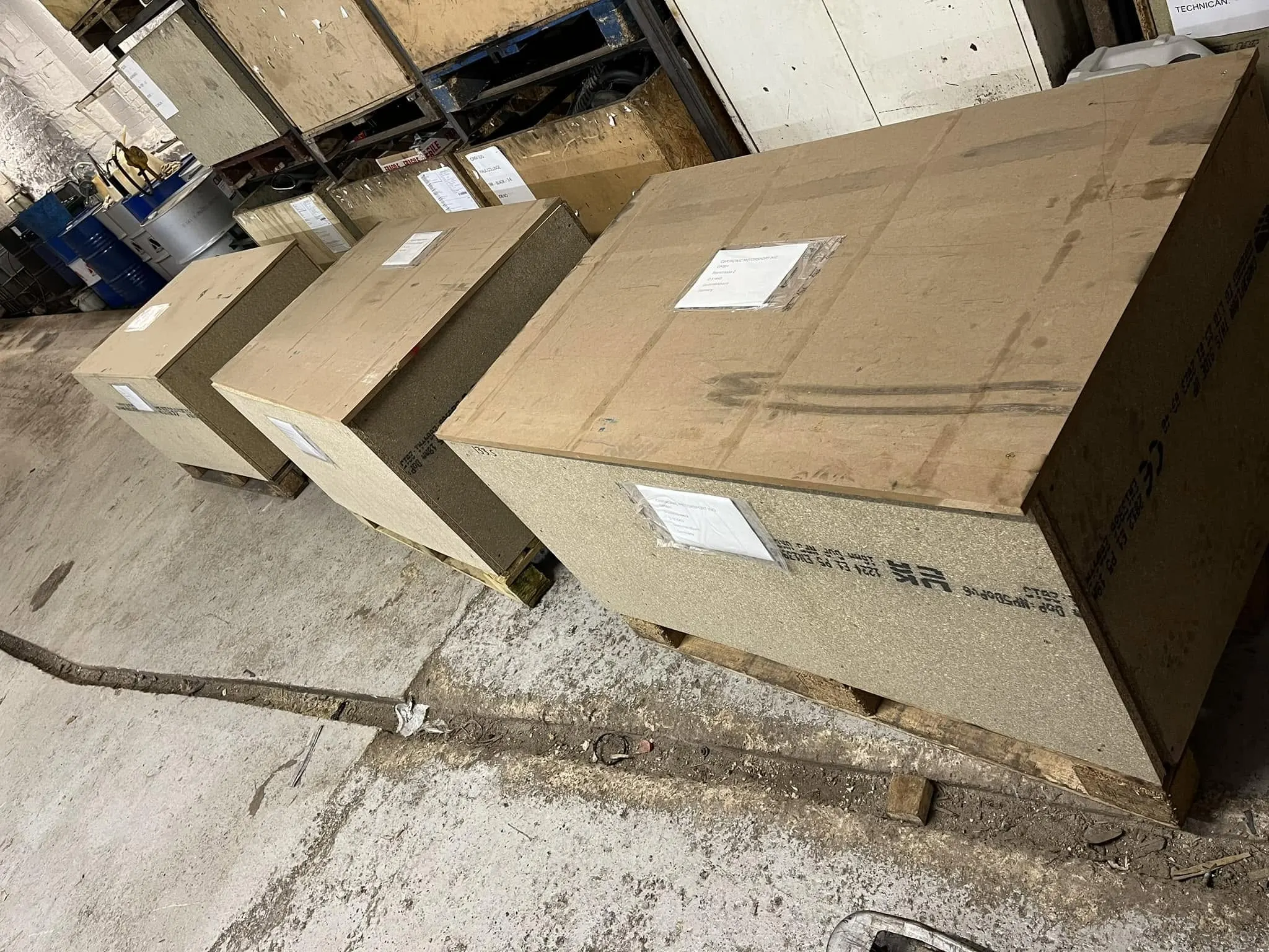 Three large boxed crates on pallets outside the workshop, ready for collection.