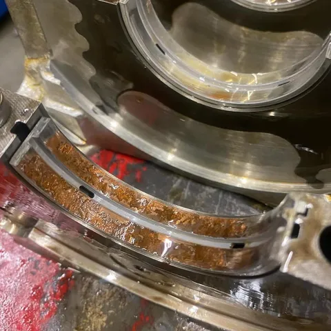 A main bearing shell in the crankcase, scored and contaminated with debris.