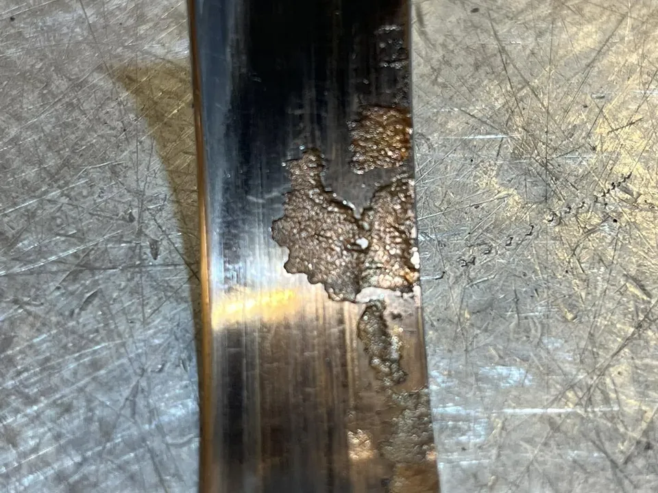 A worn crankshaft bearing shell with its overlay worn through to the copper layer beneath.