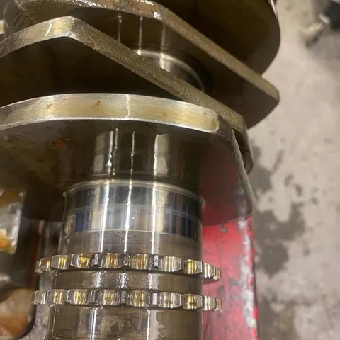Close-up of a crankshaft main journal with scoring across its surface.