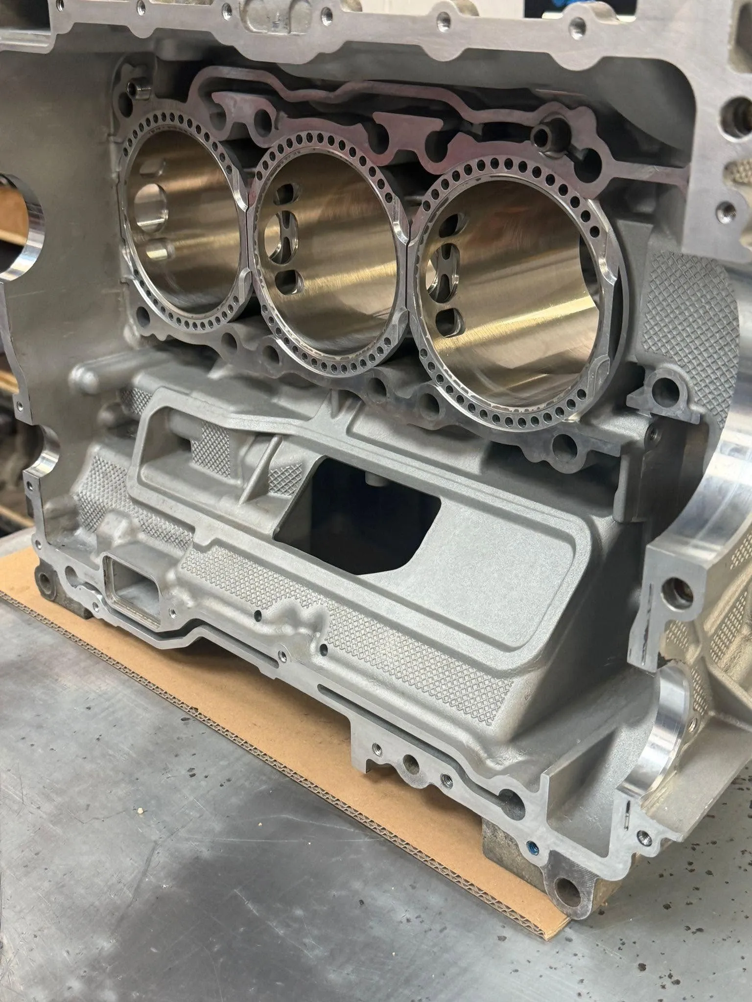 A freshly machined M96 crankcase half on the bench with three new Hartech Nikasil alloy liners fitted, viewed from the deck face.