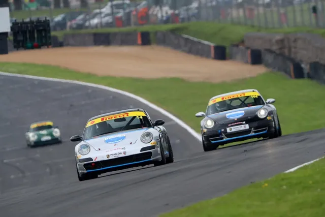 Two Hartech-liveried 911 race cars cornering together on a circuit.