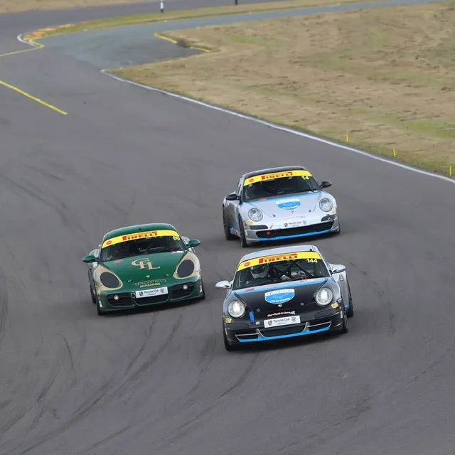 Two race-prepared Porsches on track, the leading car in Hartech blue livery.