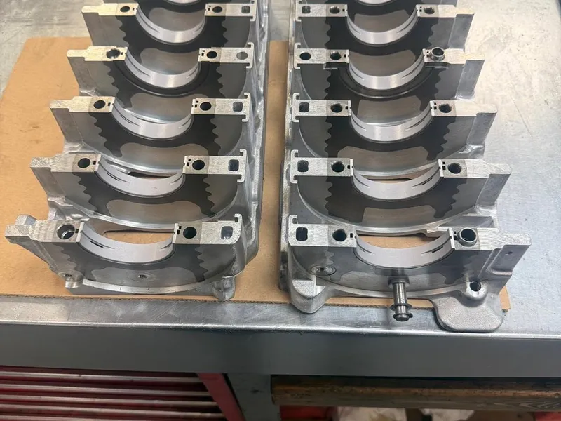 Connecting-rod bearing caps arranged in two neat rows on the bench.