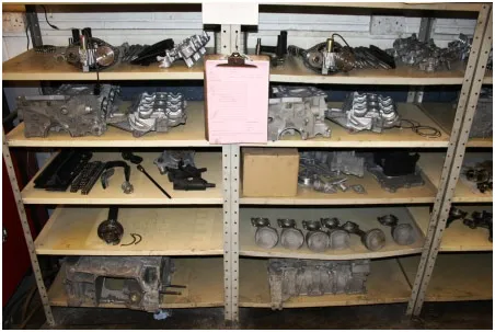 One engine fully stripped and laid out across two bays of steel racking, every component labelled.